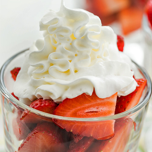 Whipped cream on a bowl of strawberries