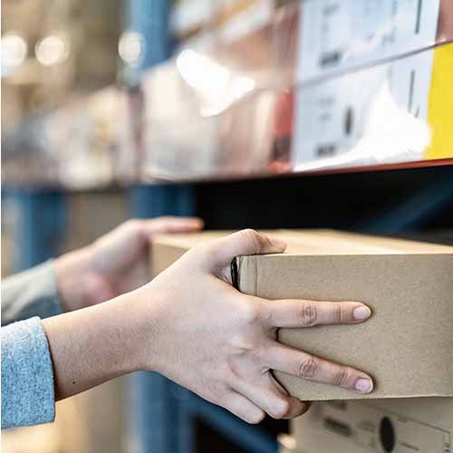 hands pulling box from warehouse shelf