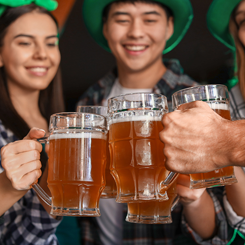 young friends with beer celebrating st patrick's day in the pub