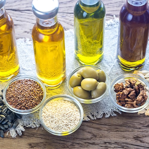 Various oils and their ingredients displayed on a wooden cutting board