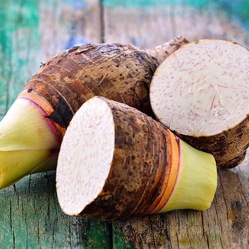 Taro roots cut open on wooden table