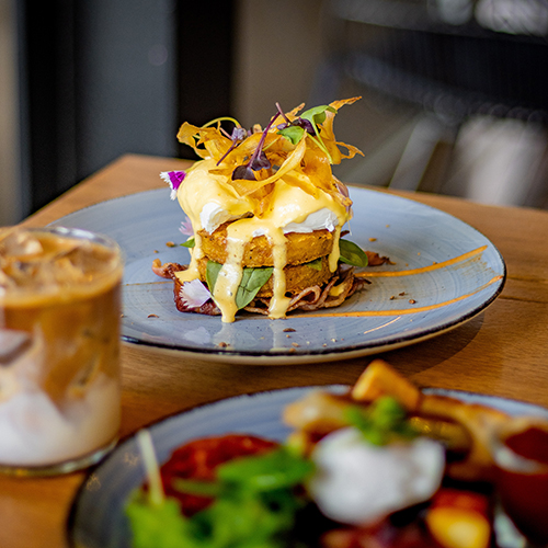 eggs benedict on a grey plate topped with edible flowers