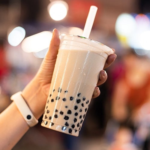 woman holding bubble tea with well lit night background