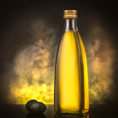 Smoked olive oil glass on black backdrop