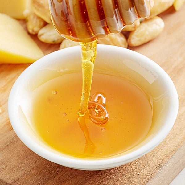 honey being drizzled into a white dish