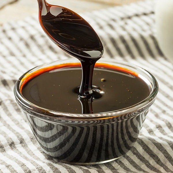 spoon dipping into a dish of black treacle