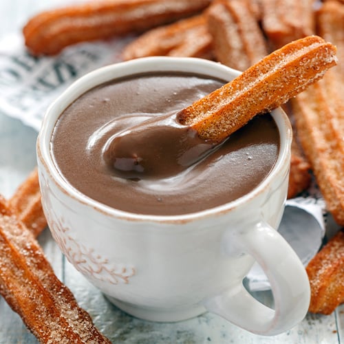 Traditional Spanish churros dipped in a cup of Spanish hot chocolate