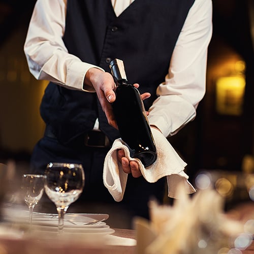 waiter presenting a bottle of red wine to a table