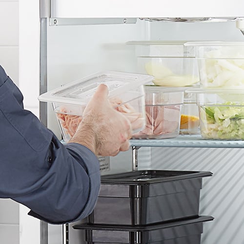 chef putting container in refrigerator to defrost