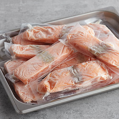 individually wrapped frozen salmon in a pan