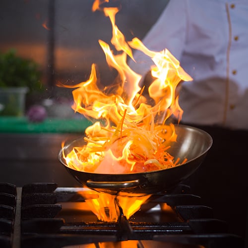 Bright fire coming out of pan as part of the flambe process