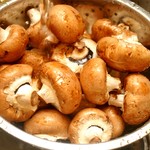 Rinsing off portabella mushrooms with water & colander