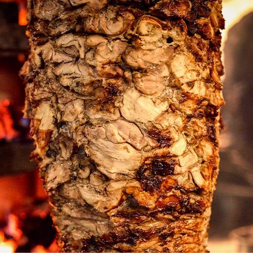 Close up of traditional gyro meat cooking on a vertical skewer