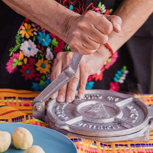 woman with traditional clothes pressing tortilla press