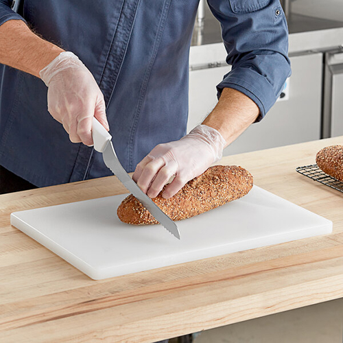 brown bread loaf being sliced on a white cutting board