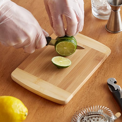 lime being sliced on a bamboo cutting board