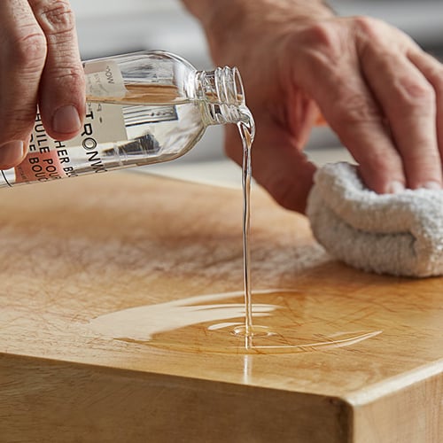 clear liquid being poured onto wood cutting board