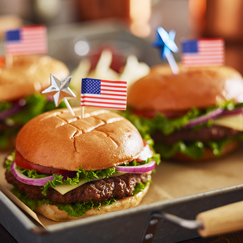 three cheeseburgers on a plate with American flag toothpicks