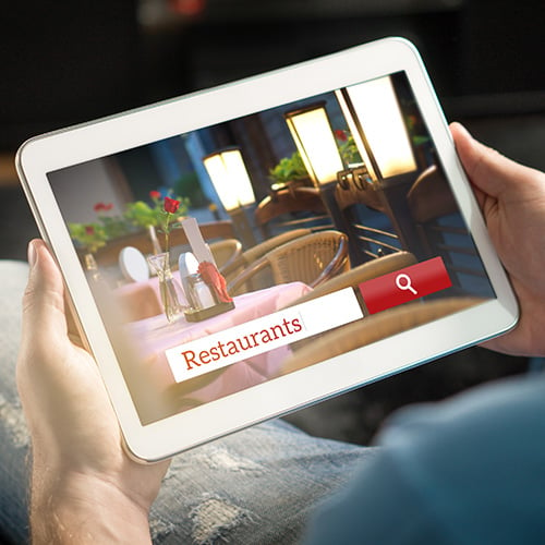 holding a tablet and using a search engine about restaurants