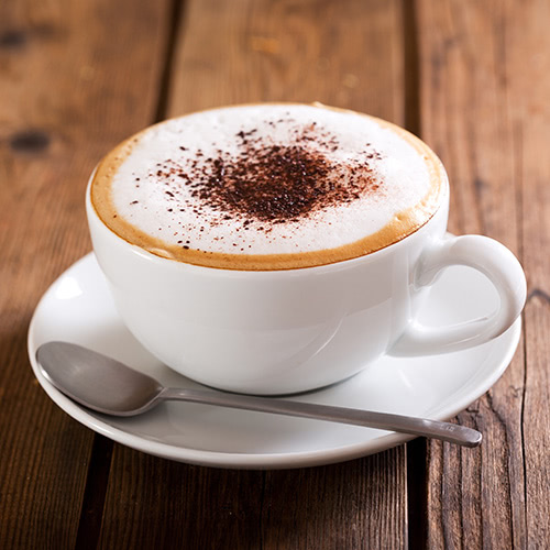 white mug with foamy cappuccino sprinkled with cocoa powder