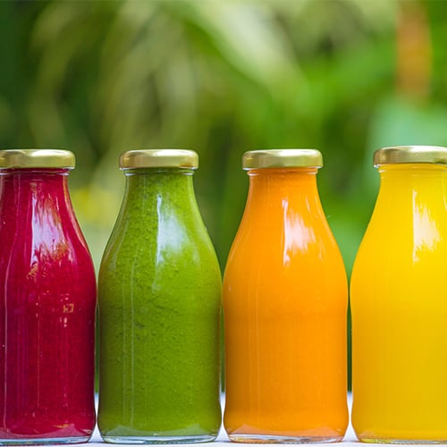 A variety of colorful Cold Pressed juice bottles in a row