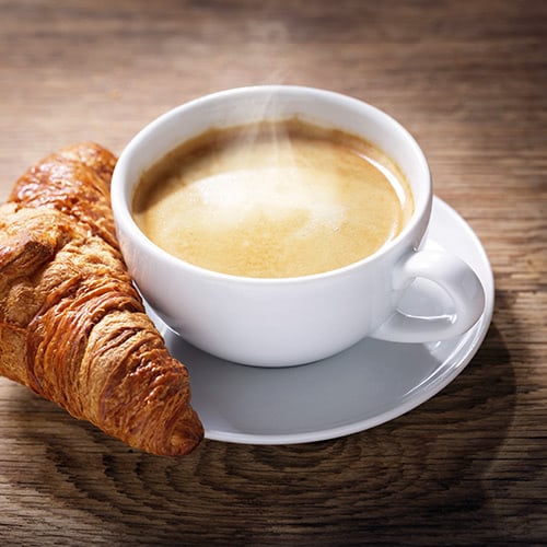 white mug with creamy hot latte and croissant on the side