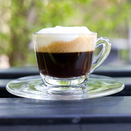 clear glass espresso mug with dark espresso topped with hot foam