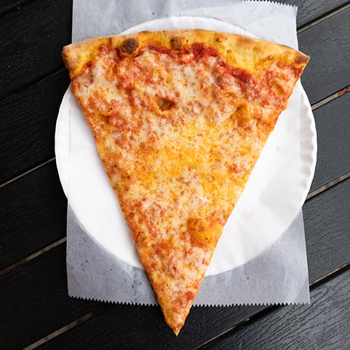 slice of New York style pizza slightly lifted out of pizza pie