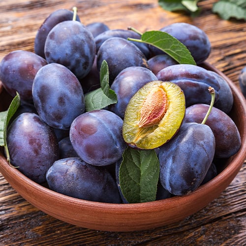 A bowl of plums on a table