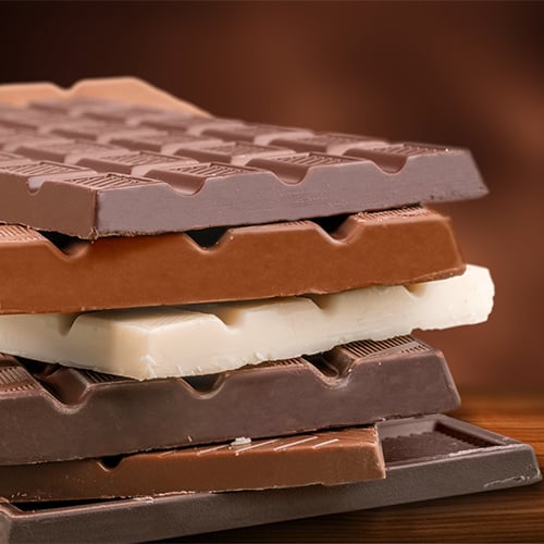 Stack of mixed dark, milk, and white chocolate bars on a wooden surface
