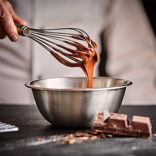 Close up of chef hand whisking melted chocolate in a bowl