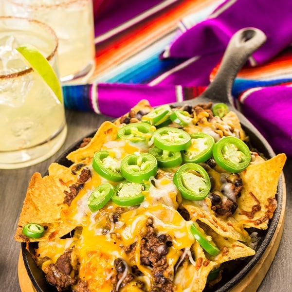Classic nachos served on a skillet with margartias and a festive table cloth