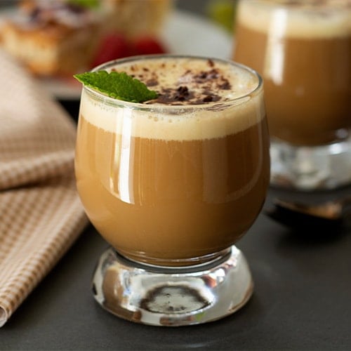 cold coffee drink in a glass garnished with cocoa and mint