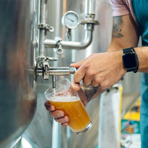 brewmaster filling glass with beer on tap