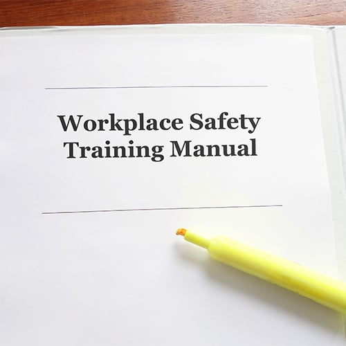 close up of employee manual with text that reads 'workplace safety training manual'