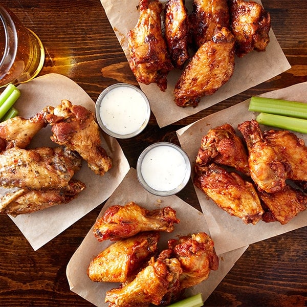 Overhead view of four orders of chicken wings with sauces
