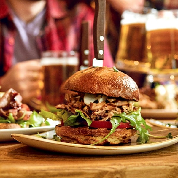 Tasty looking sandwich on a pub table with a knife through the bun