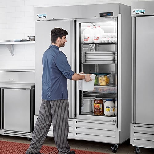 man putting a container in a commercial refrigerator