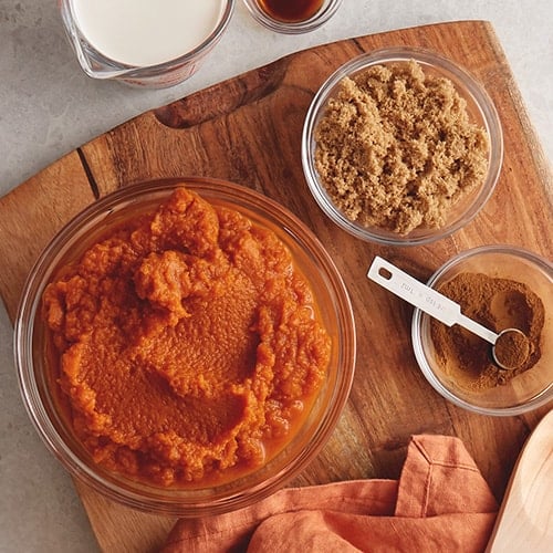 pumpkin pie filling and sugar in bowls on a cutting board