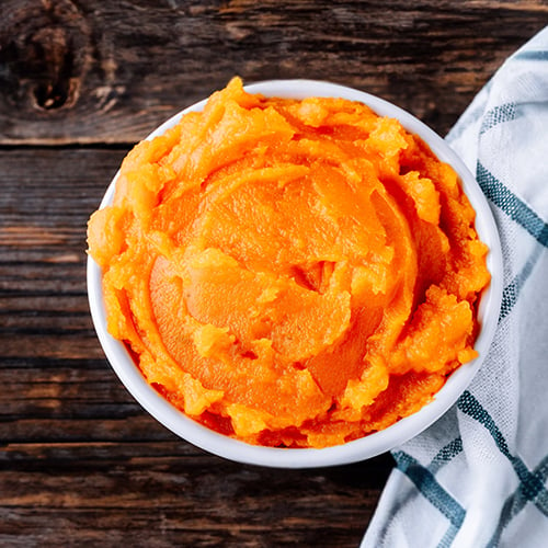 Pumpkin puree in a bowl resting on a wooden surface