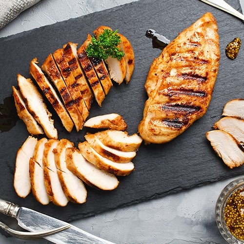 Chicken breast sliced on a black cutting board