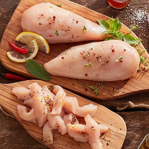 cuts of raw white and dark chicken meat on cutting boards