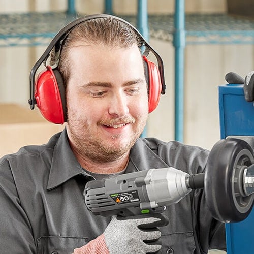 man wearing red safety ear muffs using a power drill