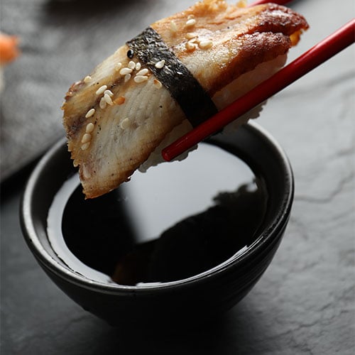 eel nigiri being dipped into eel sauce
