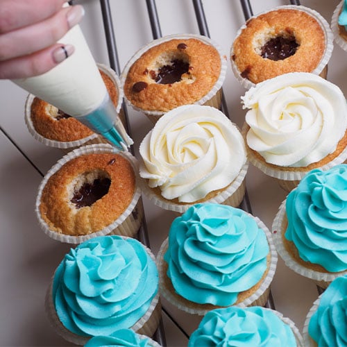 Baker piping icing on cupcakes