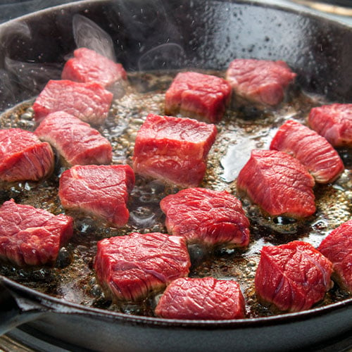 Cut meat cooking in a skillet