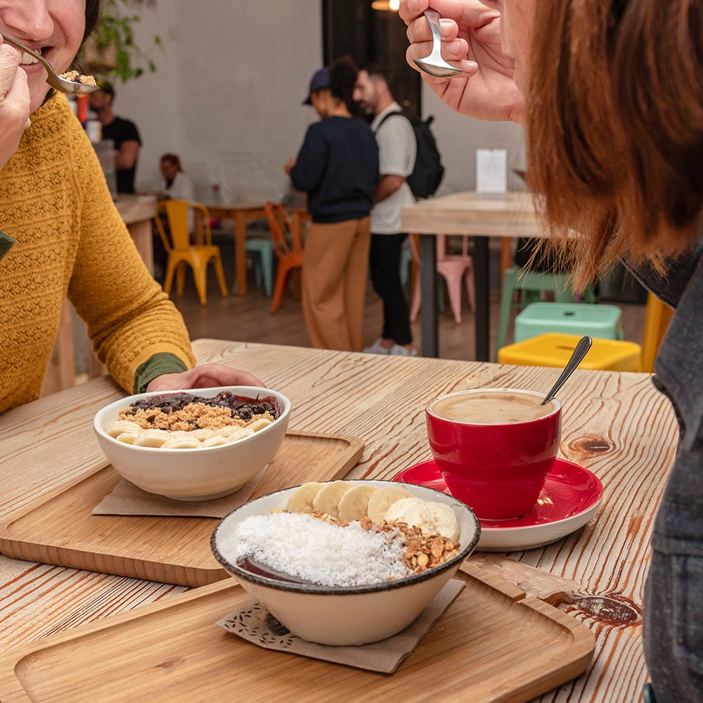 Two friends having some acai smoothie bowls and coffee for breakfast