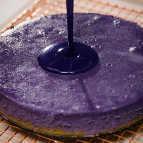 purple ganache topping being poured over cheesecake