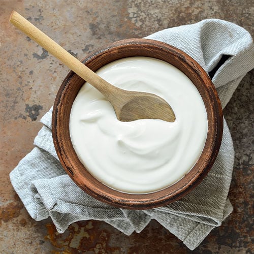 Sour Cream in a wooden bowl with a wooden spoon