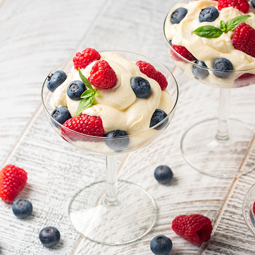 mascarpone-based pudding in a coup glass garnished with fresh raspberries and blueberries
